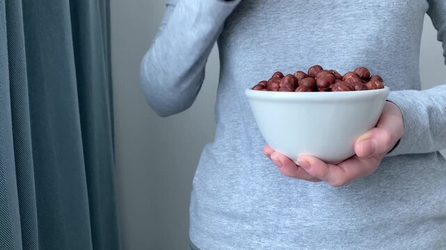 Close up. A woman takes a hazelnut from a plate. Choosing natural ingredients, avoiding animal products, and taking care of your health. The concept of vegetarianism