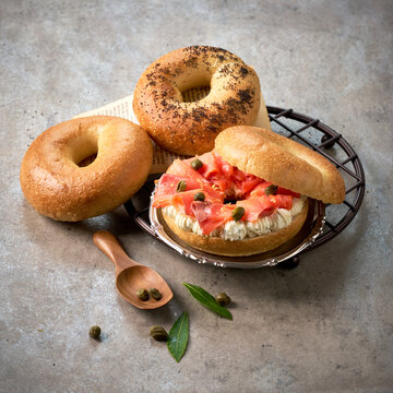 Smoked Salmon Lox Bagel Sandwich with Cream Cheese Spread and Capers Including Plain Black Sesame Poppy Seed Brunch Set Setup on Rustic Concrete Tabletop Background