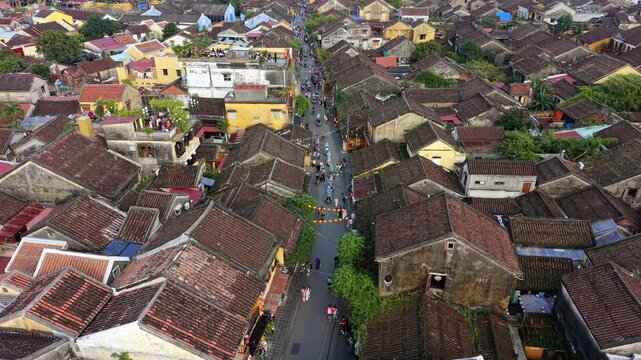 Aerial view of Hoi An old town with traditional rooftops, narrow streets, busy pedestrian life, and historic architecture, capturing vibrant daily activity in a famous Vietnamese heritage city.