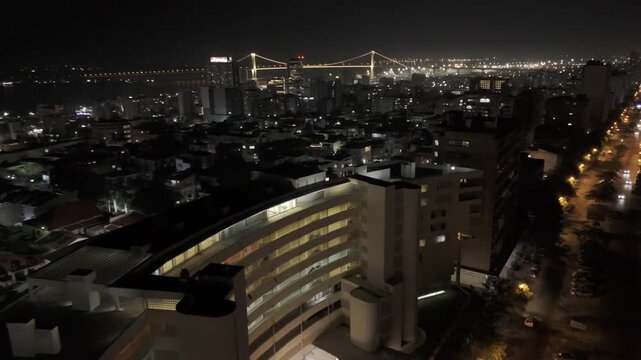 Drone flies up and away from top of apartment building on Avenida 24 de Julho at night in Maputo, Mozambique