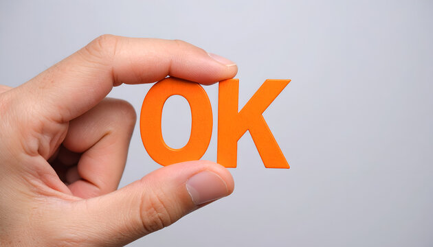 Hand holding orange OK letters, close-up shot.