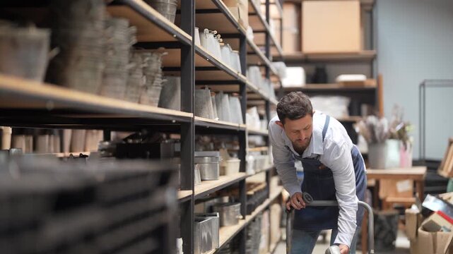 Caucasian male worker in denim apron using barcode scanner on metal bucket in small business warehouse, Retail stock management, e-commerce fulfillment, home decor logistics and supply chain concept