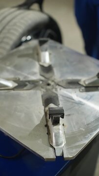 Close-up sequence of an auto mechanic using a tire changer to mount and secure a wheel, highlighting tread pattern, metal clamps, safety gloves, and precise workflow in a workshop