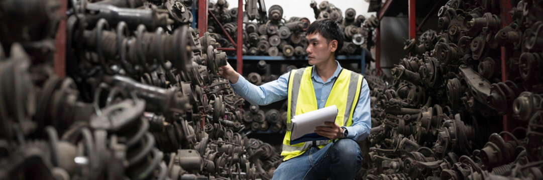 Second hand for engine parts. Asian male warehouse worker or Warehouse staff check engine car parts or second hand auto parts for reuse, repair or refurbishing recycling