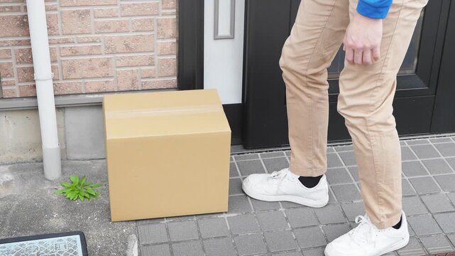 玄関前に荷物を置き配する若い宅配業者　ライフスタイルイメージ