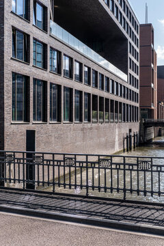 Quiet waterfront walkway frames architecture building canal railing facade windows with reflections and urban perspective plus open foreground space