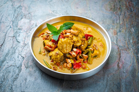 Traditional authentic Indian chicken red madras masala curry with vegetables cashew nuts served as close-up on a design plate