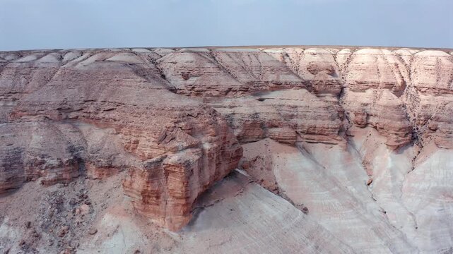 Aerial drone view of layered rock cliff, distinct sedimentary formations, erosion patterns in Bozzhyra desert, Mangistau Kazakhstan, highlighting geological structure, texture natural stratification