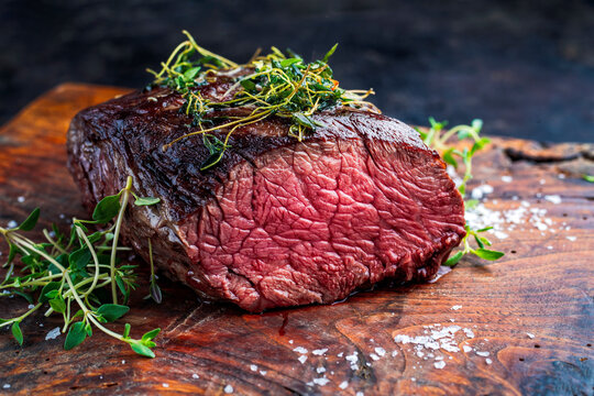 Charbroiled grilled beef steak - under-blade steak chuck roast steak, denver cut beef point steak served as close-up on wooden cutting board