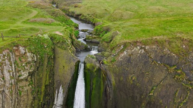 Aerial view of surroundings at Spekes Mill Mouth waterfall which is  located in a beautiful coast area of rugged valleys, high cliffs and wildflowers flourish. Drone POV of United Kingdom landscapes. 