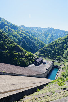 Concrete Dam and Water Channel Surrounded by Fresh Green Mountain Forest in Spring