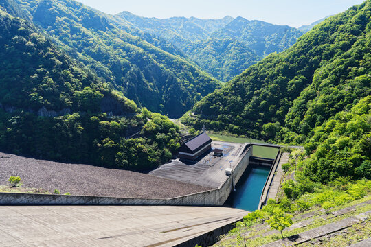 Concrete Dam Facility Surrounded by Fresh Green Mountain Forest in Spring