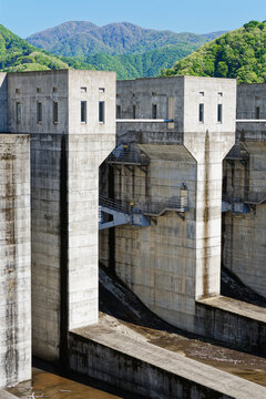 Massive Concrete Dam Structure with Mountain Forest Background in Spring