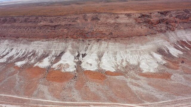aerial camera moving sideways along white limestone chalk clay cliff wide shot in Mangystau Kazakhstan, lateral motion revealing bright mineral layers and erosion patterns across dry desert terrain