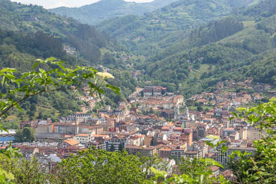 The cityscape of Mieres del Camino surrounded by green mountains in Asturias, Spain