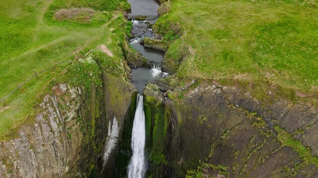Aerial view of surroundings at Spekes Mill Mouth waterfall which is  located in a beautiful coast area of rugged valleys, high cliffs and wildflowers flourish. Drone POV of United Kingdom landscapes. 