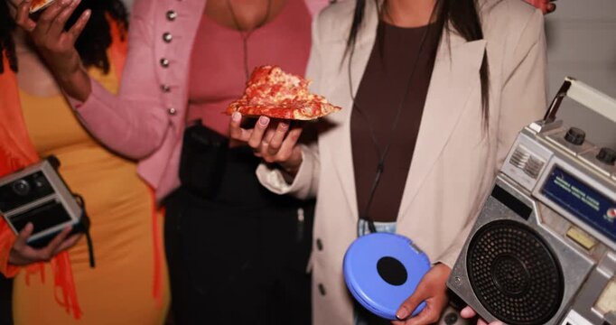 Group of multiracial young women having fun eating pizza together while listening music with retro analog devices outdoor - Party, nightlife and people lifestyle concept 