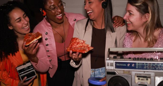 Group of multiracial young women having fun eating pizza together while listening music with analog devices outdoor - Party, nightlife and people lifestyle concept 