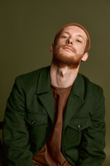 Obraz premium Stylish young man exudes confidence in green jacket against solid background