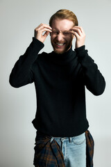 Fototapeta premium Stylish young man joyfully laughing against a simple backdrop.