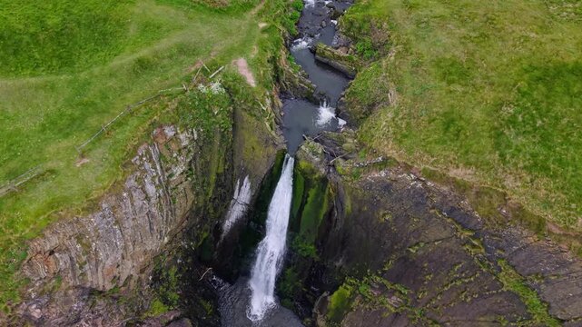 Aerial view of surroundings at Spekes Mill Mouth waterfall which is  located in a beautiful coast area of rugged valleys, high cliffs and wildflowers flourish. Drone POV of United Kingdom landscapes. 