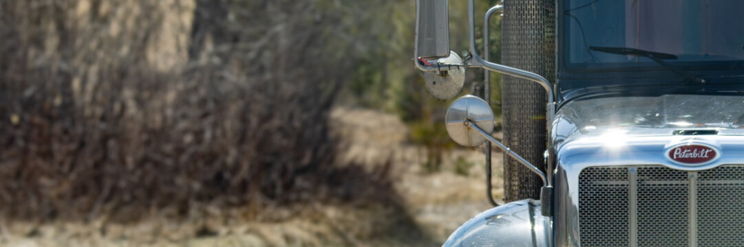 Quebec, Canada, 21 April 2026 : Front of a Peterbilt semi-truck with chrome grille and mirrors on a sunny day