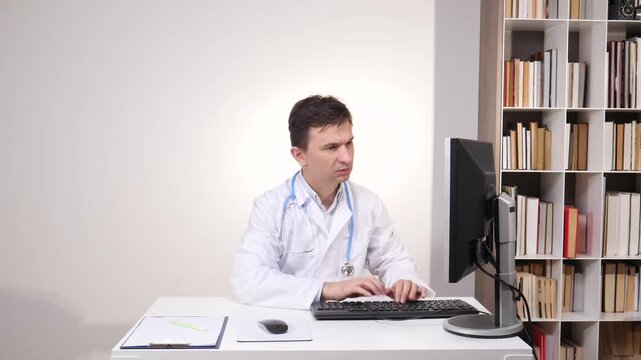 Medical professional experiencing anger and technical difficulties with technology, sitting at a desk and gesturing towards a computer monitor in a modern clinic or hospital office