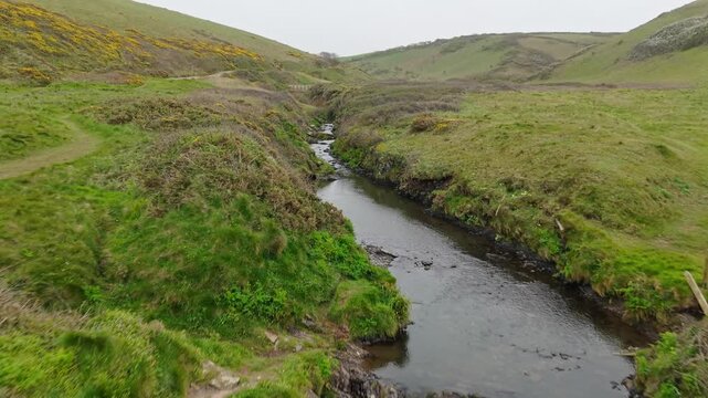 Aerial view of surroundings at Spekes Mill Mouth waterfall which is  located in a beautiful coast area of rugged valleys, high cliffs and wildflowers flourish. Drone POV of United Kingdom landscapes. 