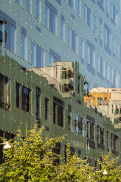 Refined pattern emerges in a modern urban architecture building where facade glass reflection greenery and trees enhance the exterior