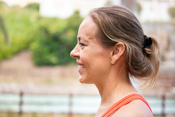 Side profile portrait of smiling mature woman during outdoor workout © chandlervid85