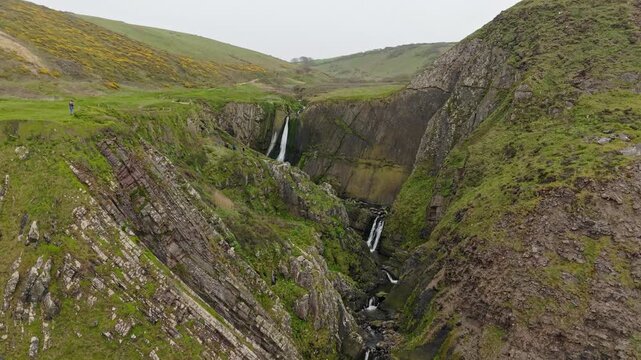 Aerial view of surroundings at Spekes Mill Mouth waterfall which is  located in a beautiful coast area of rugged valleys, high cliffs and wildflowers flourish. Drone POV of United Kingdom landscapes. 