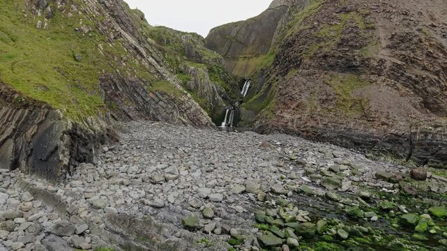 Aerial view of surroundings at Spekes Mill Mouth waterfall which is  located in a beautiful coast area of rugged valleys, high cliffs and wildflowers flourish. Drone POV of United Kingdom landscapes. 