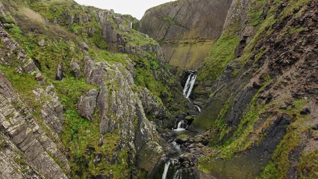 Aerial view of surroundings at Spekes Mill Mouth waterfall which is  located in a beautiful coast area of rugged valleys, high cliffs and wildflowers flourish. Drone POV of United Kingdom landscapes. 