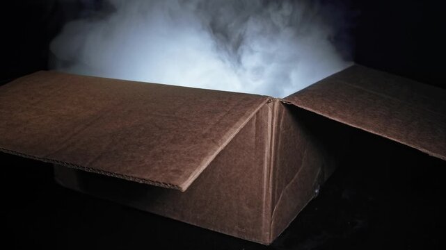 Cardboard box on dark surface emitting white smoke and mysterious light from inside, casting soft illumination on surrounding darkness, suggesting surprise, secrecy, or special delivery