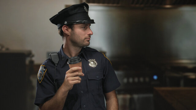 Police officer man holding coffee cup with shoulder radio in kitchen, standing and looking to the side; duty fatigue.