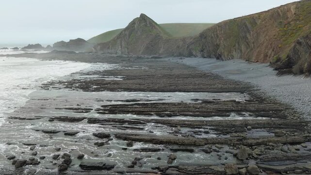 Aerial view of surroundings at Spekes Mill Mouth waterfall which is  located in a beautiful coast area of rugged valleys, high cliffs and wildflowers flourish. Drone POV of United Kingdom landscapes. 