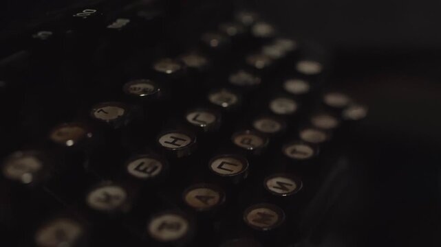 Detailed close-up shot of old mechanical typewriter keyboard buttons featuring Cyrillic letters. Focus on worn surface of keys, suggesting history and extensive use of antique writing machine. Dark, n