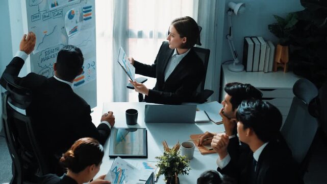 Top view of smart manager compare chart between board and paper while planning startup project with group of diverse team at business meeting. Team brainstorming and working together. Directorate.