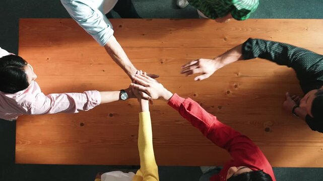 Close up of happy start up business people hand putting hands together at meeting and clapping hand to celebrate collaboration and increasing sales or encourage teamwork and togetherness. Convocation.