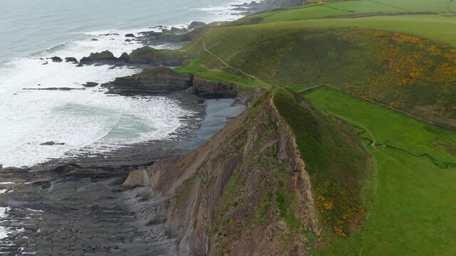 Aerial view of surroundings at Spekes Mill Mouth waterfall which is  located in a beautiful coast area of rugged valleys, high cliffs and wildflowers flourish. Drone POV of United Kingdom landscapes. 
