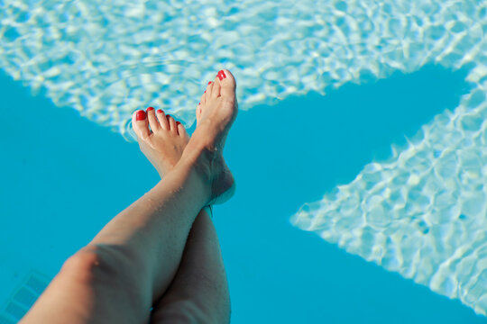 Crossed legs over blue swimming pool