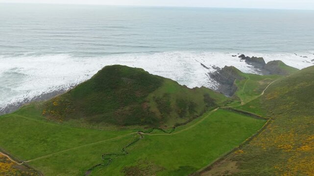Aerial view of surroundings at Spekes Mill Mouth waterfall which is  located in a beautiful coast area of rugged valleys, high cliffs and wildflowers flourish. Drone POV of United Kingdom landscapes. 
