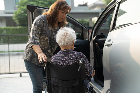 Caregiver help Asian elderly woman disability patient get in her car.