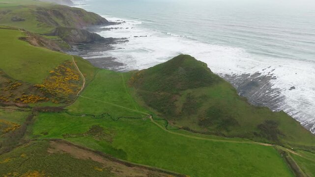 Aerial view of surroundings at Spekes Mill Mouth waterfall which is  located in a beautiful coast area of rugged valleys, high cliffs and wildflowers flourish. Drone POV of United Kingdom landscapes. 
