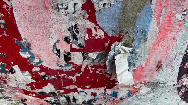 Close up video of a torn old poster peel from a weathered wall fluttering in the wind, creating an urban textured abstract background