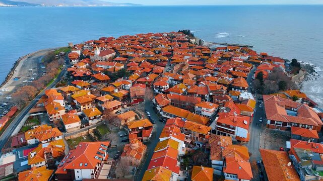 Aerial panorama of old town located on narrow peninsula. Wide angle drone shot of a densely built historic city surrounded by the blue sea under clear sky.