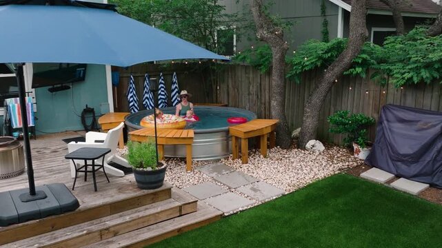 family playing in backyard pool deck umbrella, turf yard, Luxury outdoor living ads, summer lifestyle, and home property content aerial wide drone shot 4k