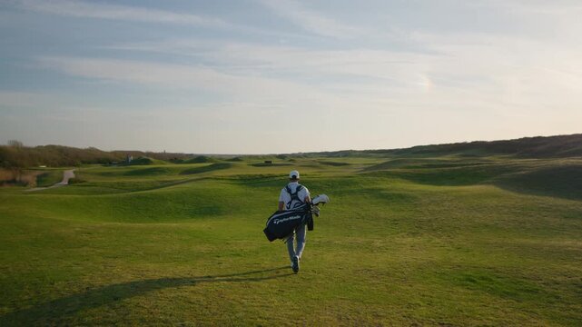 Rear View of Golfer with Golf Bag Walking on Beautiful Green revealing Course