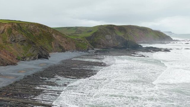 Aerial view of surroundings at Spekes Mill Mouth waterfall which is  located in a beautiful coast area of rugged valleys, high cliffs and wildflowers flourish. Drone POV of United Kingdom landscapes.