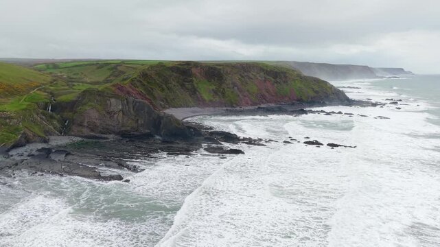 Aerial view of surroundings at Spekes Mill Mouth waterfall which is  located in a beautiful coast area of rugged valleys, high cliffs and wildflowers flourish. Drone POV of United Kingdom landscapes. 